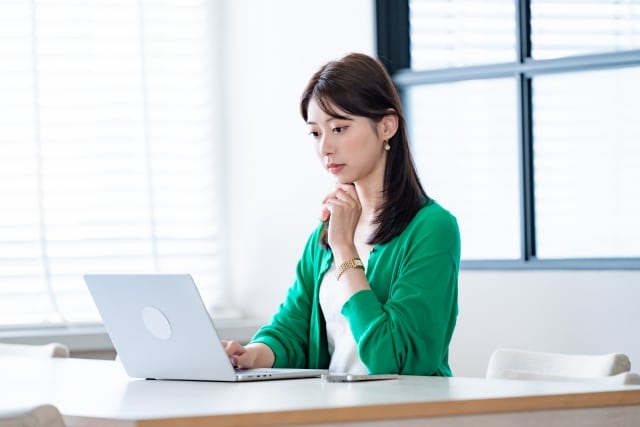 PCを見て考える女性
