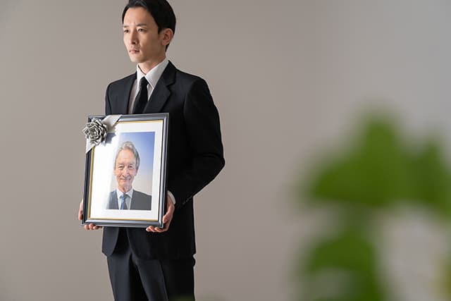 遺影を持つ男性