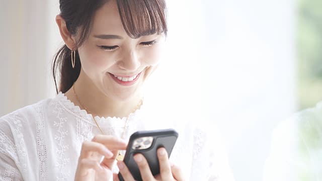 スマホを笑顔で操作する女性
